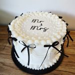 Traditional black and white single tier Mr and Mrs wedding cake with piped and pearl detail and black bows