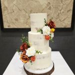 Semi iced three tier wedding cake with bronzed autumnal floral decoration