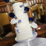 Butter iced three tier wedding cake with shades of blue floral decoration