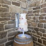 Beautiful three tier wedding cake on an old whisky barrel with natural stone back drop